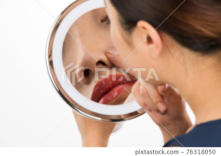 一個女人在鏡子裡看著她的鼻子 一個女人在鏡子裡看著她的鼻子 76318050