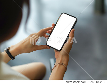 Over shoulder closeup view of female hands using mock-up smartphone screen Over shoulder closeup view of female hands using mock-up smartphone screen 76318349