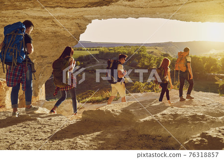 Group of young tourists hikers hiking in natural rocks with backpacks Group of young tourists hikers hiking in natural rocks with backpacks 76318857