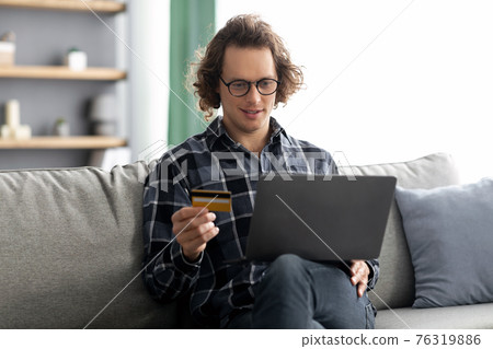 Guy Using Credit Card And Laptop Shopping Online At Home Guy Using Credit Card And Laptop Shopping Online At Home 76319886