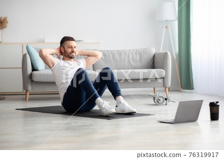 Smiling man working on abs, using laptop 76319917