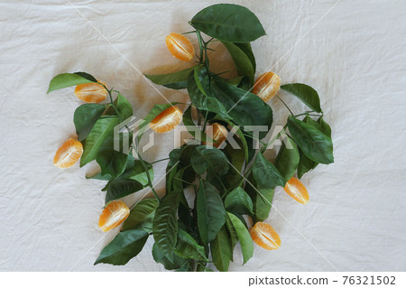 Clementines tangerines and twig with green leaves as spring decor on white cloth background. Clementines tangerines and twig with green leaves as spring decor on white cloth background. 76321502