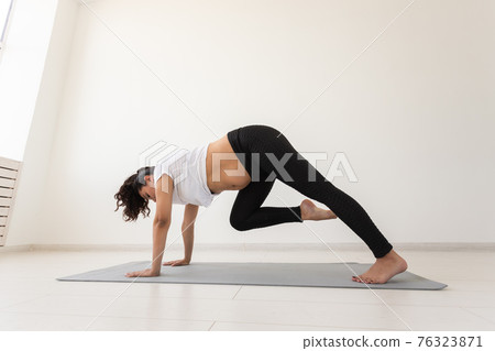 Young flexible pregnant woman doing gymnastics on rug on the floor on white background. The concept of preparing the body for easy childbirth Young flexible pregnant woman doing gymnastics on rug on the floor on white background. The concept of preparing the body for easy childbirth 76323871