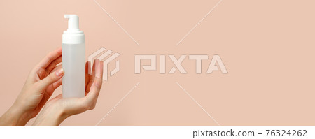 Female hand with cosmetic product in bottle on neutral beige trendy background, concept of helathcare, hygiene, dispenser with soap or antiseptic antimicrobial gel, banner, copy space 76324262