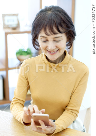 Senior woman operating a smartphone 76324757