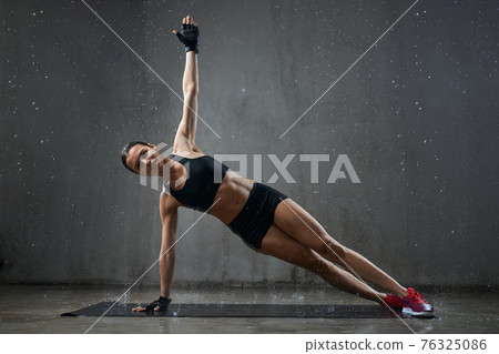 Muscular woman practicing side plank exercise. Muscular woman practicing side plank exercise. 76325086