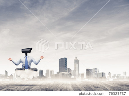 Camera headed man sitting in lotus pose on cloud against modern 76325787