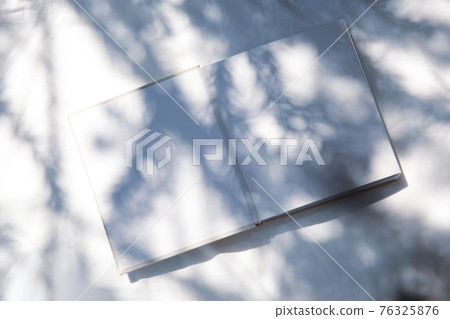 A book placed on a white fabric with natural light and the shadows of plants A book placed on a white fabric with natural light and the shadows of plants 76325876