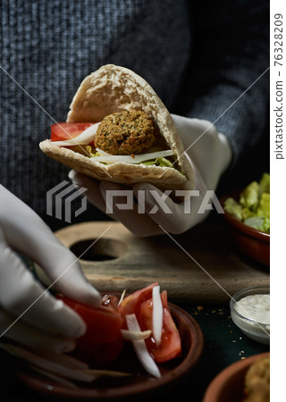 man preparing a falafel sandwich 76328209