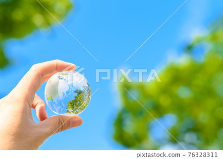 Hold the earth over the beautiful blue sky and fresh green 76328311