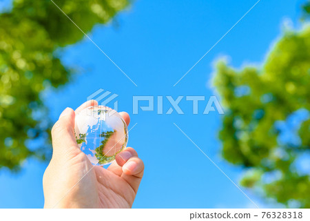 Hold the earth over the beautiful blue sky and fresh green 76328318