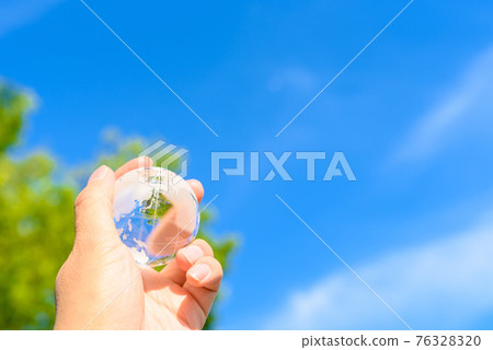 Hold the earth over the beautiful blue sky and fresh green 76328320