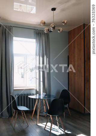 Stylish dining room with modern chairs and table by the window Stylish dining room with modern chairs and table by the window 76328369