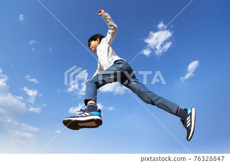 Boy jumping against the blue sky 76328847