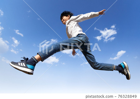 Boy jumping against the blue sky Boy jumping against the blue sky 76328849