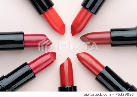 Red lipsticks of different shades arranged in a circle on beige background. Makeup and cosmetics concept. Close up. Flat layout. Red lipsticks of different shades arranged in a circle on beige background. Makeup and cosmetics concept. Close up. Flat layout. 76329056