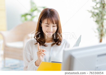 Woman doing desk work in a bright room Woman doing desk work in a bright room 76330054