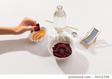 Dried dragon fruit chips and sauce on white background with womans hand Dried dragon fruit chips and sauce on white background with womans hand 76332390