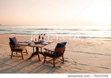 Romantic breakfast on beach. Breakfast table with island sunrise Romantic breakfast on beach. Breakfast table with island sunrise 76333340