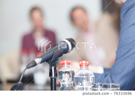 Microphone in focus against blurred people at roundtable event Microphone in focus against blurred people at roundtable event 76333696