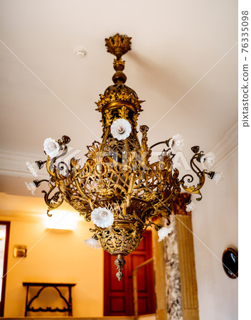 Antique gold chandelier with patterns. Royal interiors of castles. Antique gold chandelier with patterns. Royal interiors of castles. 76335098