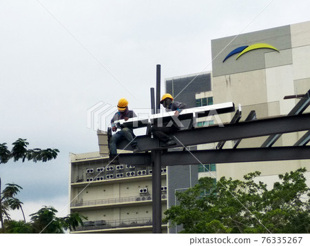 MALACCA, MALAYSIA -MARCH 14, 2020: Construction workers working at height at the construction site. They are supplied with harnesses and other safety equipment to prevent them from having an accident. MALACCA, MALAYSIA -MARCH 14, 2020: Construction workers working at height at the construction site. They are supplied with harnesses and other safety equipment to prevent them from having an accident. 76335267