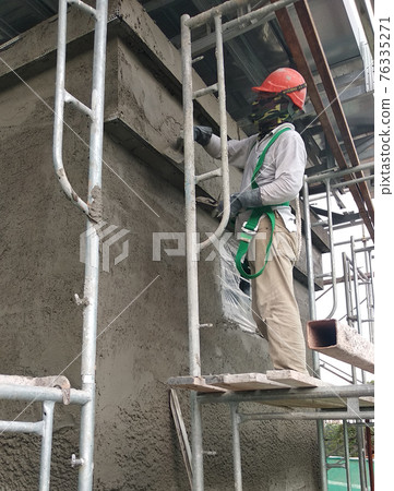 MALACCA, MALAYSIA -MARCH 14, 2020: Construction workers working at height at the construction site. They are supplied with harnesses and other safety equipment to prevent them from having an accident. 76335271