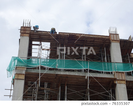 MALACCA, MALAYSIA -MARCH 14, 2020: Construction workers working at height at the construction site. They are supplied with harnesses and other safety equipment to prevent them from having an accident. MALACCA, MALAYSIA -MARCH 14, 2020: Construction workers working at height at the construction site. They are supplied with harnesses and other safety equipment to prevent them from having an accident. 76335307
