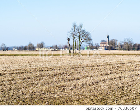 rural landscape with harvested fileld and village 76336507