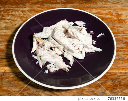deboned fillet of baked fish on dark plate 76336536