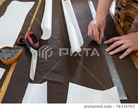 woman draws pattern on brown fabric with rule woman draws pattern on brown fabric with rule 76336763