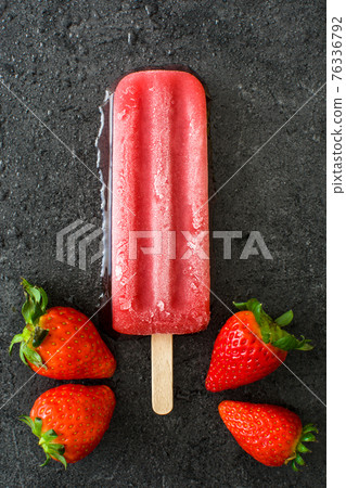 Strawberry popsicle on black stone 76336792