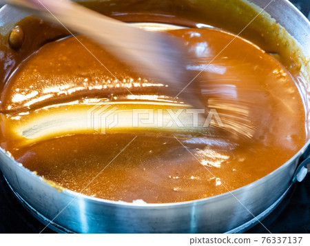 cooking salted butter caramel sauce at home kitchen - stirring hot smooth prepared salty caramel dessert with wooden culinary spatula in steel pan cooking salted butter caramel sauce at home kitchen - stirring hot smooth prepared salty caramel dessert with wooden culinary spatula in steel pan 76337137