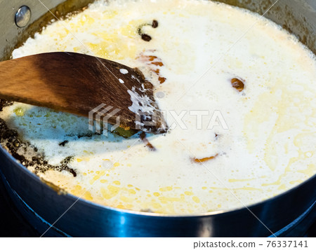 cooking salted butter caramel sauce at home kitchen - mixture of melted sugar and butter with added cream in steel pan close up cooking salted butter caramel sauce at home kitchen - mixture of melted sugar and butter with added cream in steel pan close up 76337141