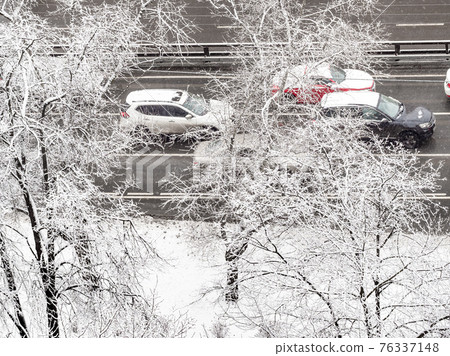 aerial view through snowy trees cars on wet road 76337148