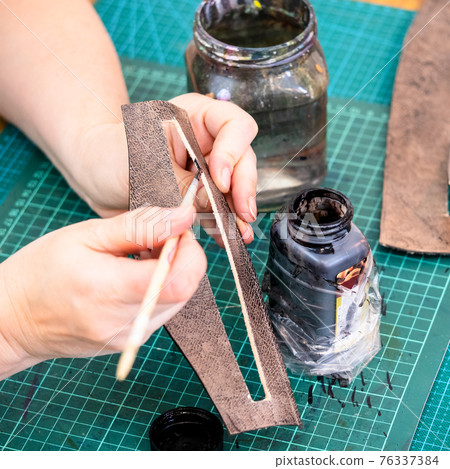 craftsman tones the edges of carved leather item 76337384