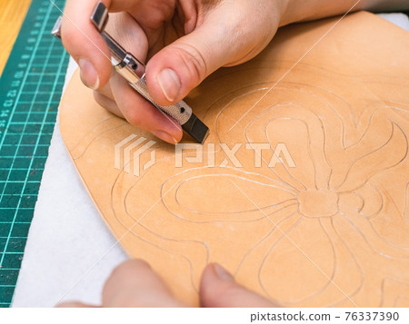 craftsman carves drawn floral ornament on leather craftsman carves drawn floral ornament on leather 76337390