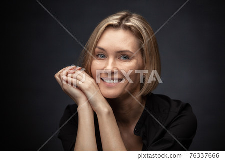 Beautiful middle-aged woman on a gray background in a black blouse. Beautiful middle-aged woman on a gray background in a black blouse. 76337666