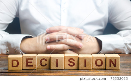 Man folded his hands on a background of blocks with the word Decision. Make the right decision, the answer to the question. Reasoning, weighing results and consequences. Authoritative opinion. Man folded his hands on a background of blocks with the word Decision. Make the right decision, the answer to the question. Reasoning, weighing results and consequences. Authoritative opinion. 76338023
