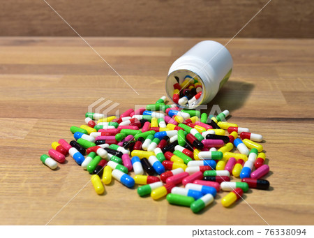 Pills from a plastic bottle on wooden background. Pills from a plastic bottle on wooden background. 76338094