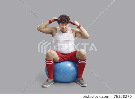 Funny angry chubby man sitting on fitness ball and getting ready for gym workout Funny angry chubby man sitting on fitness ball and getting ready for gym workout 76338270