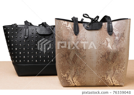 two fashionable women's handbags, on a white background, one is black, the other is beige made of reptile skin two fashionable women's handbags, on a white background, one is black, the other is beige made of reptile skin 76339048