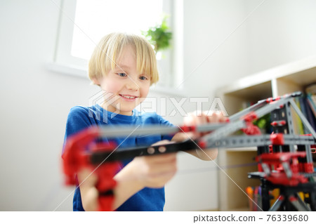 Preschooler boy playing with big construction building crane toy at home. Kids leisure activity. Entertainment for children indoors. Creative game, development of imagination. Preschooler boy playing with big construction building crane toy at home. Kids leisure activity. Entertainment for children indoors. Creative game, development of imagination. 76339680