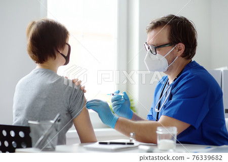 Doctor or nurse is preparing to give a injection vaccine against covid-19 to a woman. Mass vaccination. Herd immunity 76339682