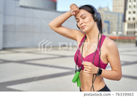 Sporty young woman with wireless headphones in training Sporty young woman with wireless headphones in training 76339983