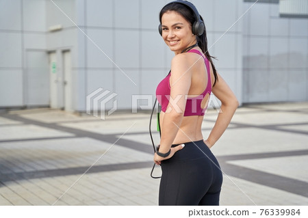Attractive lady in sportswear using wireless headphones Attractive lady in sportswear using wireless headphones 76339984