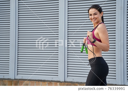 Smiling attractive lady doing a workout with a skipping rope Smiling attractive lady doing a workout with a skipping rope 76339991