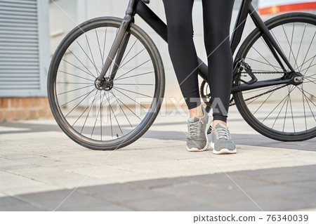 Young woman with black bike in the city Young woman with black bike in the city 76340039