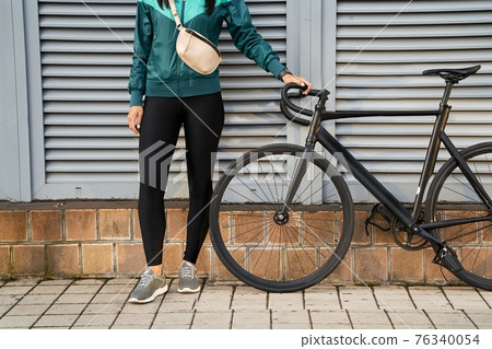 Lady in black leggings holding the bicycle handlebar Lady in black leggings holding the bicycle handlebar 76340054