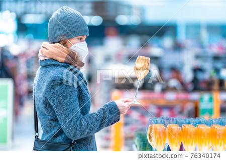 buy wine glasses by a young woman in a store 76340174